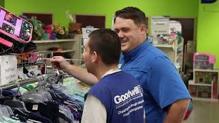 Media 18 Male goodwill employees smiling while they browse near the clothes racks
