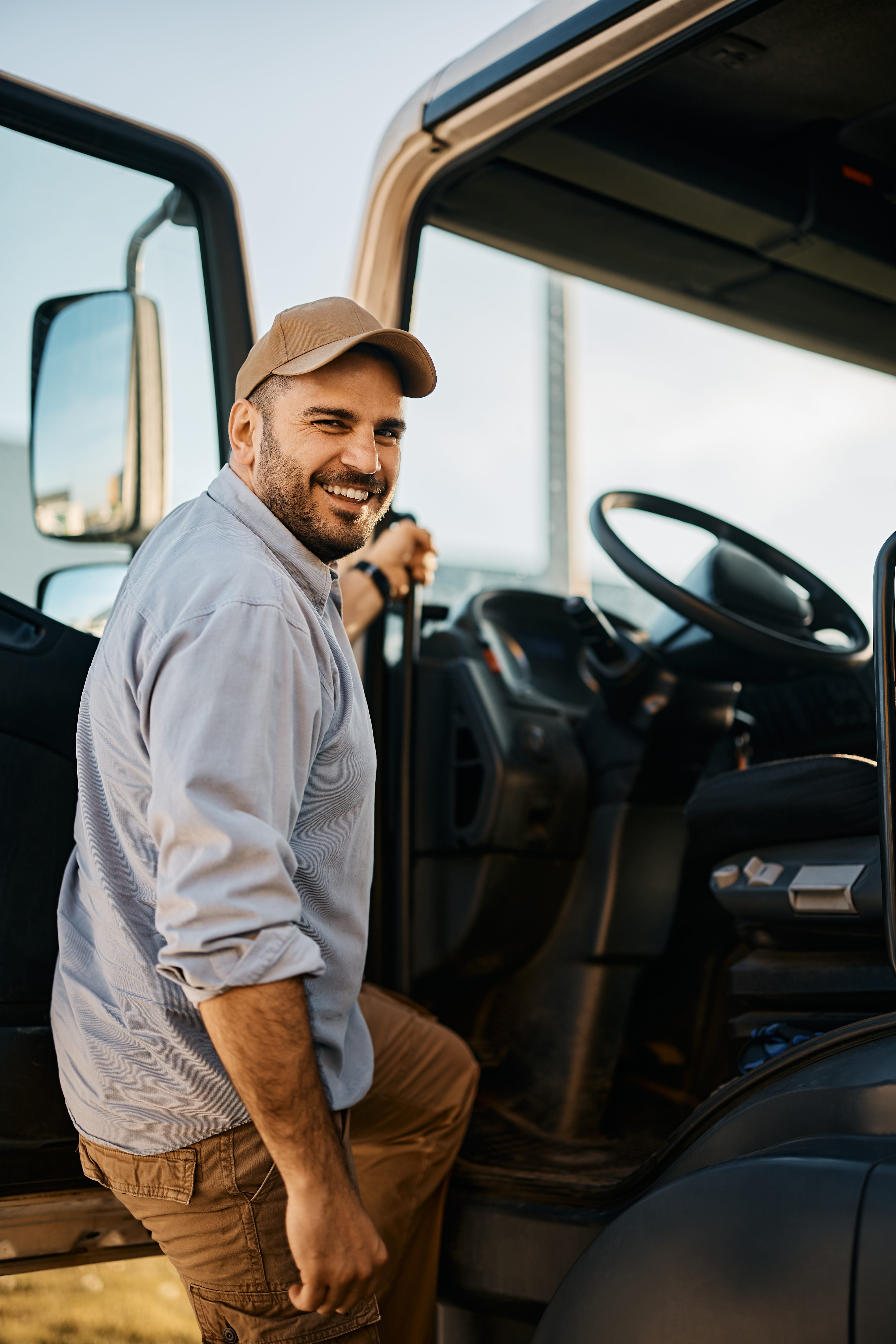 Happy truck driver entering in vehicle cabin and looking at camera. Adobestock 503962118 1